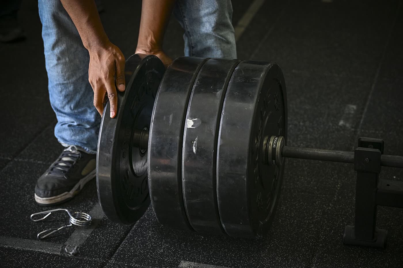 Loading weight plates onto a barbell in a gym